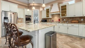 Une cuisine moderne avec des meubles blancs, des plans de travail en granit et des appareils électroménagers en acier inoxydable.