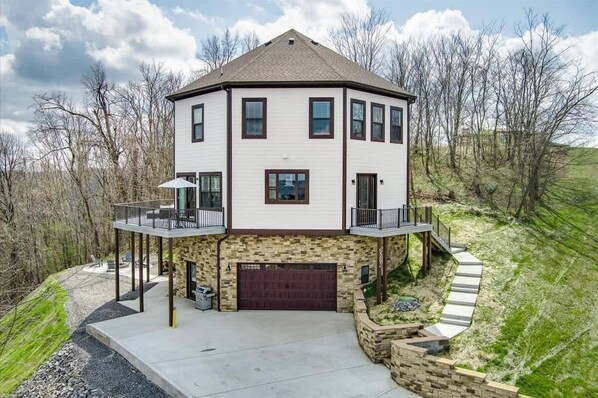 A two-story house with a stone foundation, a garage, and a balcony.