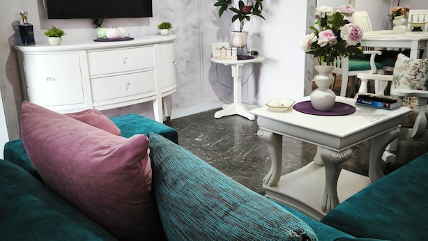 A modern living room with teal sofas, a white console table, a TV, and a decorative mirror. - Ένα ευχάριστο χώρο άνετο και εξυπηρέτηκο έχει όλες της άνεσης...μέσα στην πόλη.. (Kastelli)