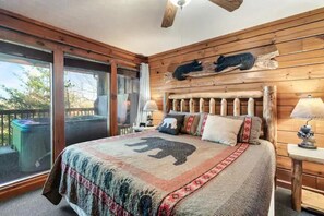 A bedroom with a large bed, wooden headboard, and a view of the outdoors. - King Bed, Pool Table, Hot tub, Vinyl Record Player, Covered Back Porch w VIEWS!! (Sevierville)