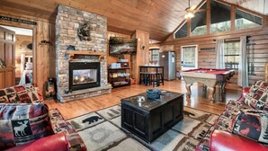A cozy cabin interior with a stone fireplace, a pool table, and a comfortable seating area. - King Bed, Pool Table, Hot tub, Vinyl Record Player, Covered Back Porch w VIEWS!! (Sevierville)