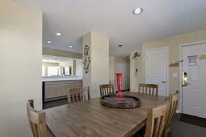 A dining area with a wooden table, six chairs, and a red decorative piece.