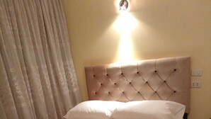 Una habitación de hotel con una cama, una lámpara fijada a la pared y un suelo estampado.