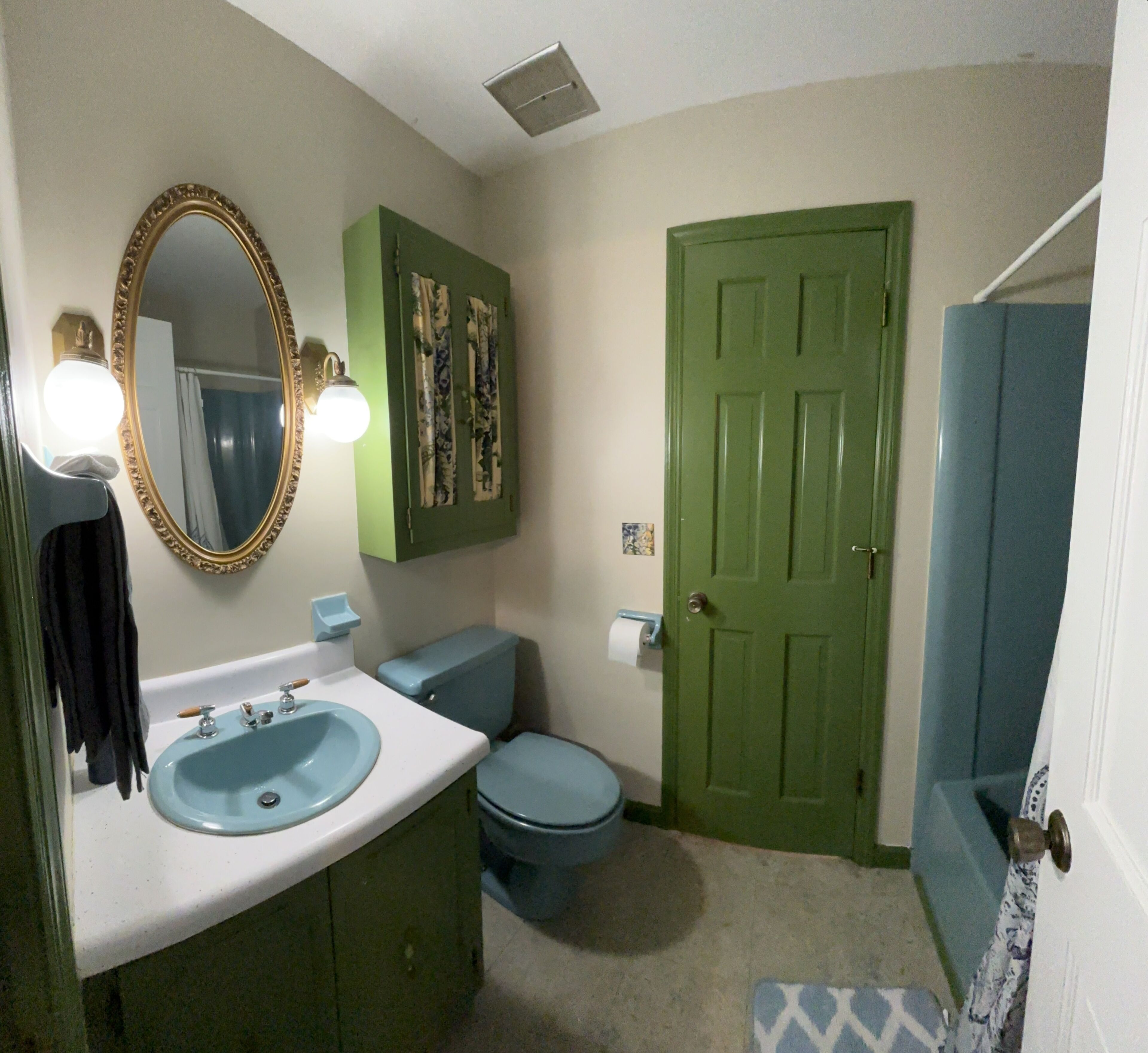 Une salle de bain avec un lavabo, des toilettes et une porte verte.