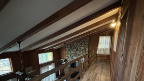 A wooden staircase with a stone wall and a view of the outdoors.