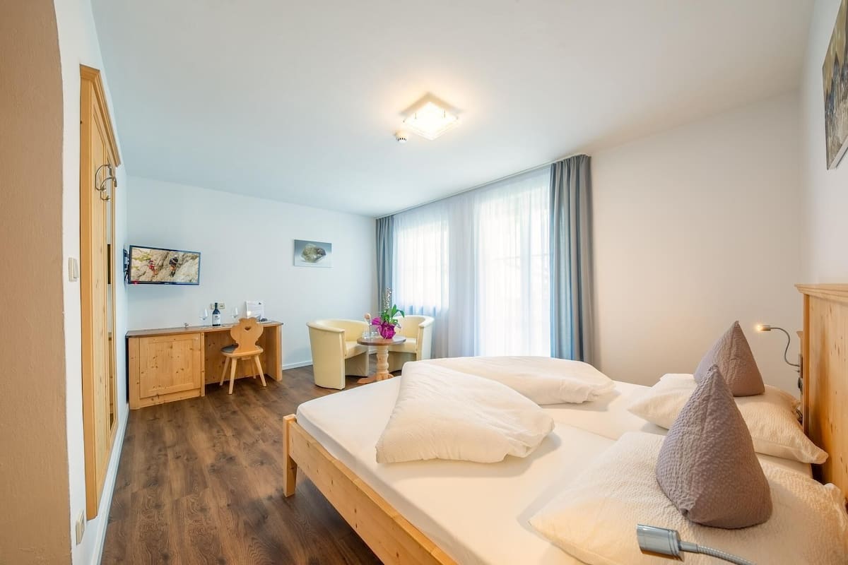 Une chambre d’hôtel avec un grand lit, un bureau, une chaise et une petite table.