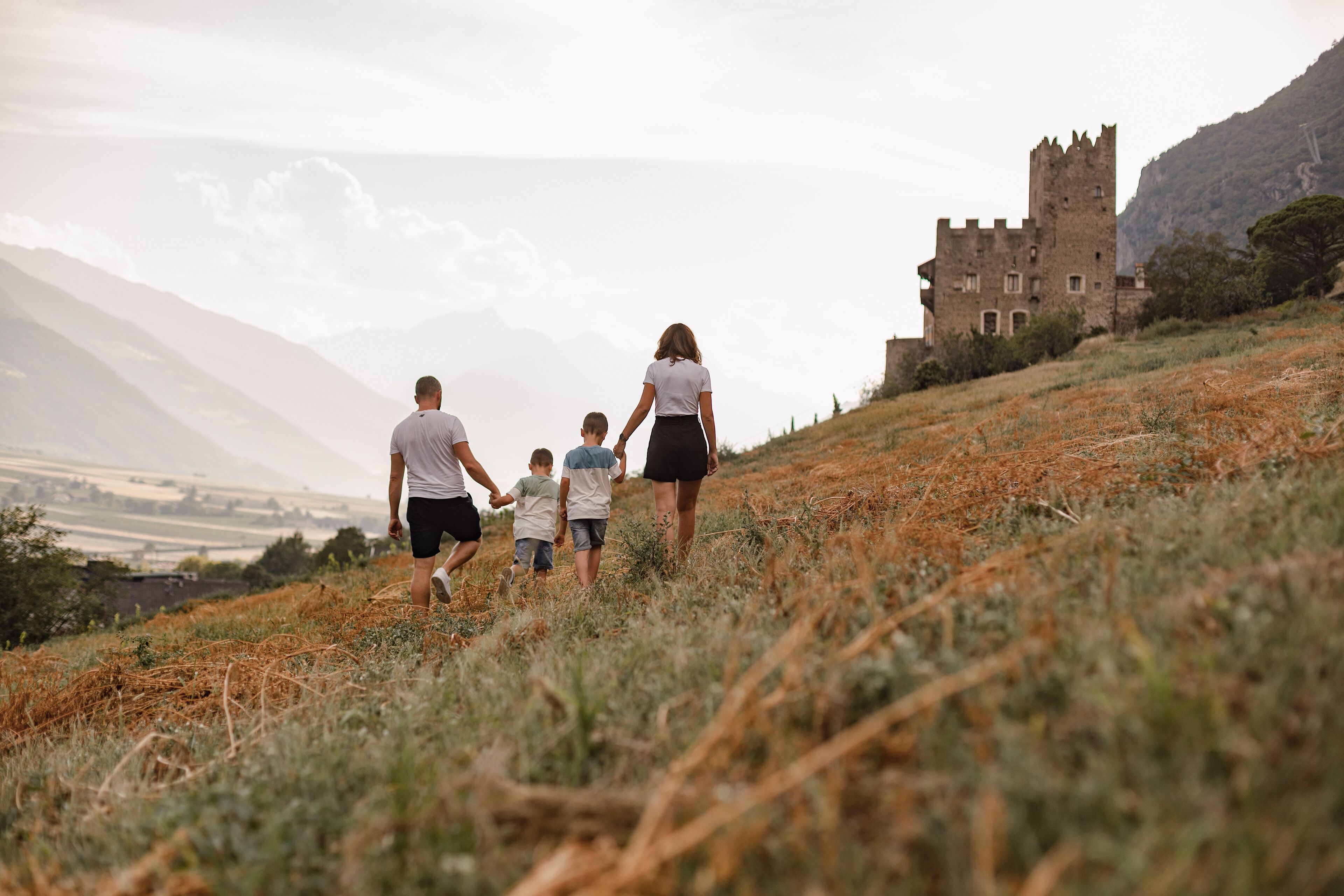 Una familia caminando sobre una colina cubierta de pasto, con un castillo al fondo.