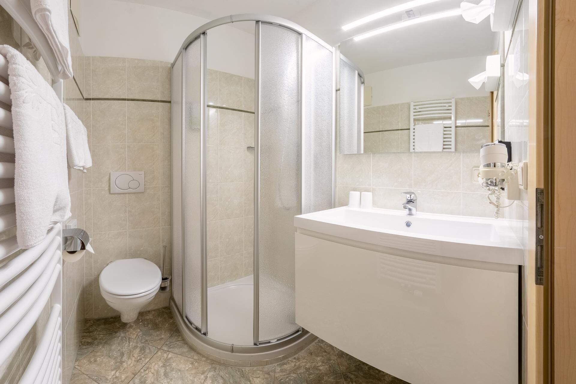 Ein modernes Badezimmer mit einer Duschkabine, einer Toilette und einem Waschbecken inklusive Spiegel.