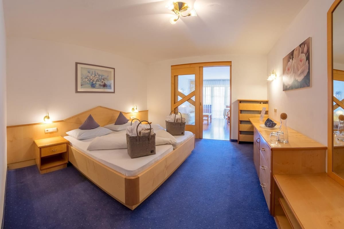 Une chambre d’hôtel avec un lit en bois, une table de chevet, un bureau avec un miroir et une vue sur l’extérieur.