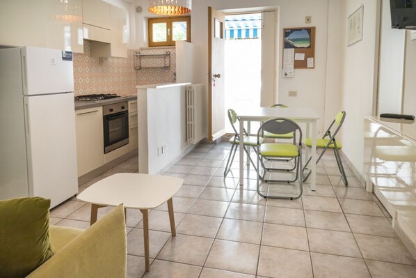 Una cocina compacta con refrigerador, estufa, horno y un comedor con mesa y sillas.