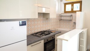 A kitchen with white cabinets, a gas stove, an oven, and a white countertop. - M377 - Marcelli, two-room apartment with external courtyard and parking (Marcelli)