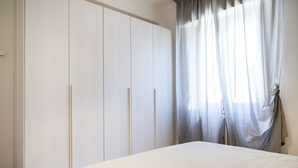 A bedroom with a bed, a wardrobe, and a window with curtains. - M377 - Marcelli, two-room apartment with external courtyard and parking (Marcelli)