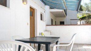 A patio with a table and chairs, a door, and a striped awning. - M377 - Marcelli, two-room apartment with external courtyard and parking (Marcelli)