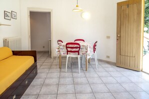 A room with a bed, a table with chairs, a wooden door, and a radiator. - M376 - Marcelli, two-room apartment with parking space (Marcelli)
