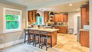 A spacious kitchen with a central island, wooden cabinets, and a large window.