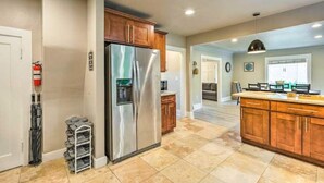 A spacious kitchen with a stainless steel refrigerator, wooden cabinets, and a tiled floor.