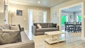 A spacious living room with a grey sofa, a coffee table, and a dining area with a table and chairs.