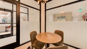 A modern meeting room with a round table and four chairs, large windows with glass partitions, and a visible exit sign. - New penthouse unit in downtown Bellevue (Bellevue)