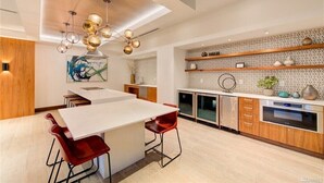 A modern kitchen with a central island, red bar stools, a hanging light fixture, and a tiled backsplash. - New penthouse unit in downtown Bellevue (Bellevue)