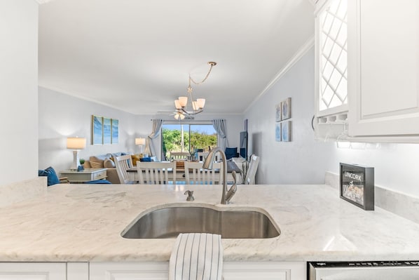 A modern kitchen with a marble countertop, stainless steel sink, and a built-in dishwasher.