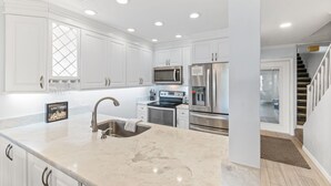 Una cocina moderna con armarios blancos, electrodomésticos de acero inoxidable y encimera de mármol.