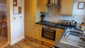 Una cocina con armarios de madera, una campana extractora de acero inoxidable, un horno empotrado, un tostador y un escurreplatos.