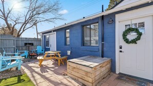 Une maison bleue avec une porte blanche, un banc en bois et une table de pique-nique.