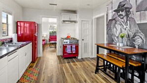 Une cuisine avec un réfrigérateur rouge, une cuisinière à gaz et une table à manger avec des bancs.
