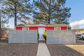 A red building with a white door, surrounded by a gravel driveway and two white gates. - Downtown Berry Bungalows - 2 Single Family Homes w/Fenced Yards, AC, W/D, Wi-Fi (Flagstaff)