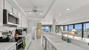 Una cocina moderna con una isla grande, electrodomésticos integrados y vistas al océano.