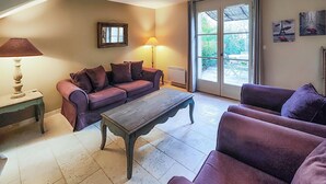Una sala de estar con un sofá, una mesa de centro de madera, una lámpara y vistas a través de un ventanal.