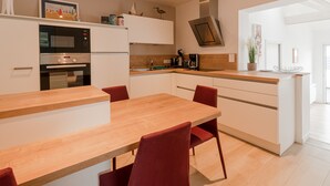 Eine moderne Küche mit Holztisch und roten Stühlen, inklusive eingebautem Backofen und einer Kaffeemaschine.