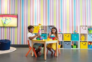 Two children playing with building blocks at a table in a brightly colored room with striped wallpaper and storage boxes. - Incredible 2-Bedroom Ocean View Suite at Garza Blanca 5-Star Resort: Los Cabos (Cabo San Lucas)