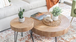 Een moderne woonkamer met een grote ronde salontafel, twee bijzettafeltjes en een bank.