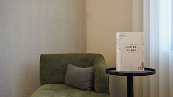 A green sofa with a pillow, a small round table with a menu sign, and a patterned wall.