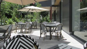 An outdoor seating area with tables and chairs, surrounded by greenery. - Hotel Antré Chapultepec (Guadalajara)
