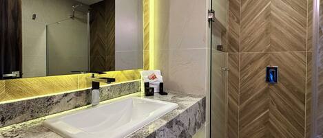 A modern bathroom with a large mirror, a white sink, and a shower area.