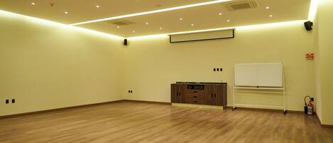 A spacious room with wooden flooring, a whiteboard, and a fire extinguisher.