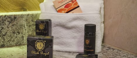 Black Royal soap and lotion boxes, a bar of soap, and a box of orange-flavored lotion on a bathroom counter.