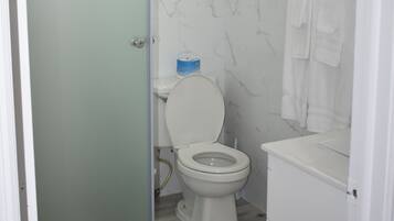 A bathroom with a toilet, a glass shower enclosure, and a white sink.