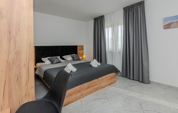 Un dormitorio moderno con una cama grande, ropa de cama gris y un cabecero de madera.