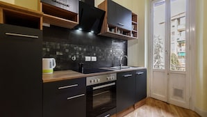 A modern kitchen with black cabinets, a wooden countertop, a built-in oven, and a window overlooking a residential area. - Fabbroni 3 bedrooms in Florence by Mmega (Firenze)
