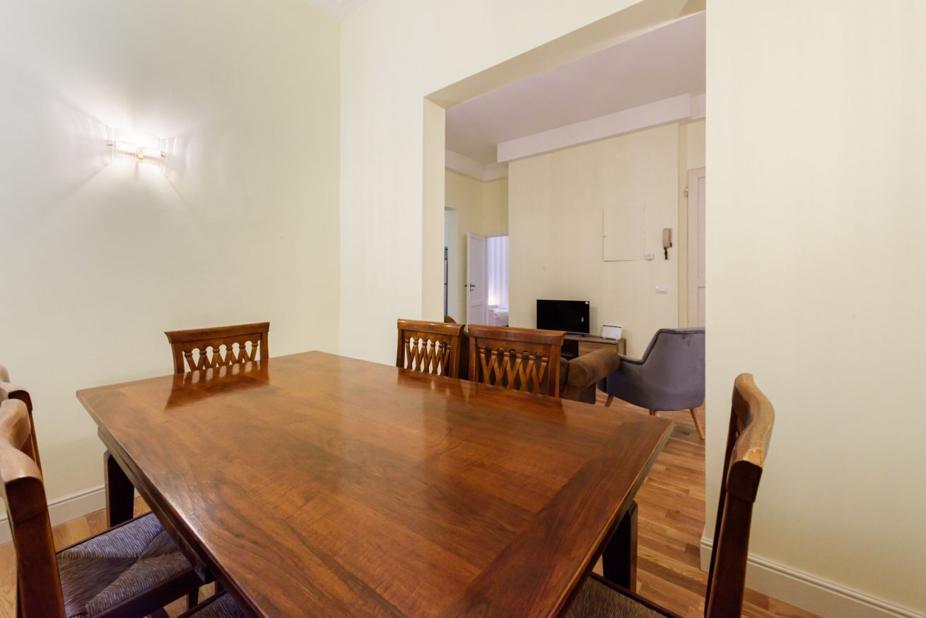 A dining area with a wooden table and chairs, a television, and a door leading to another room.