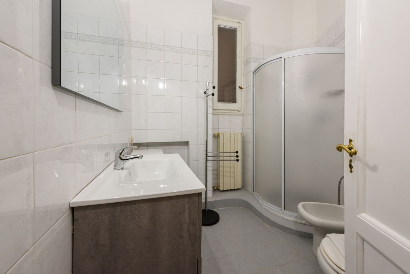 A bathroom with a white sink, a mirror, a shower, and a toilet.