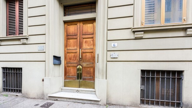 A building with a double wooden door, a small set of steps leading up to it, and a barred window to the right. - Fabbroni 3 bedrooms in Florence by Mmega (Firenze)