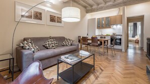 A modern living room with a sofa, coffee table, and a dining area with chairs and a table.