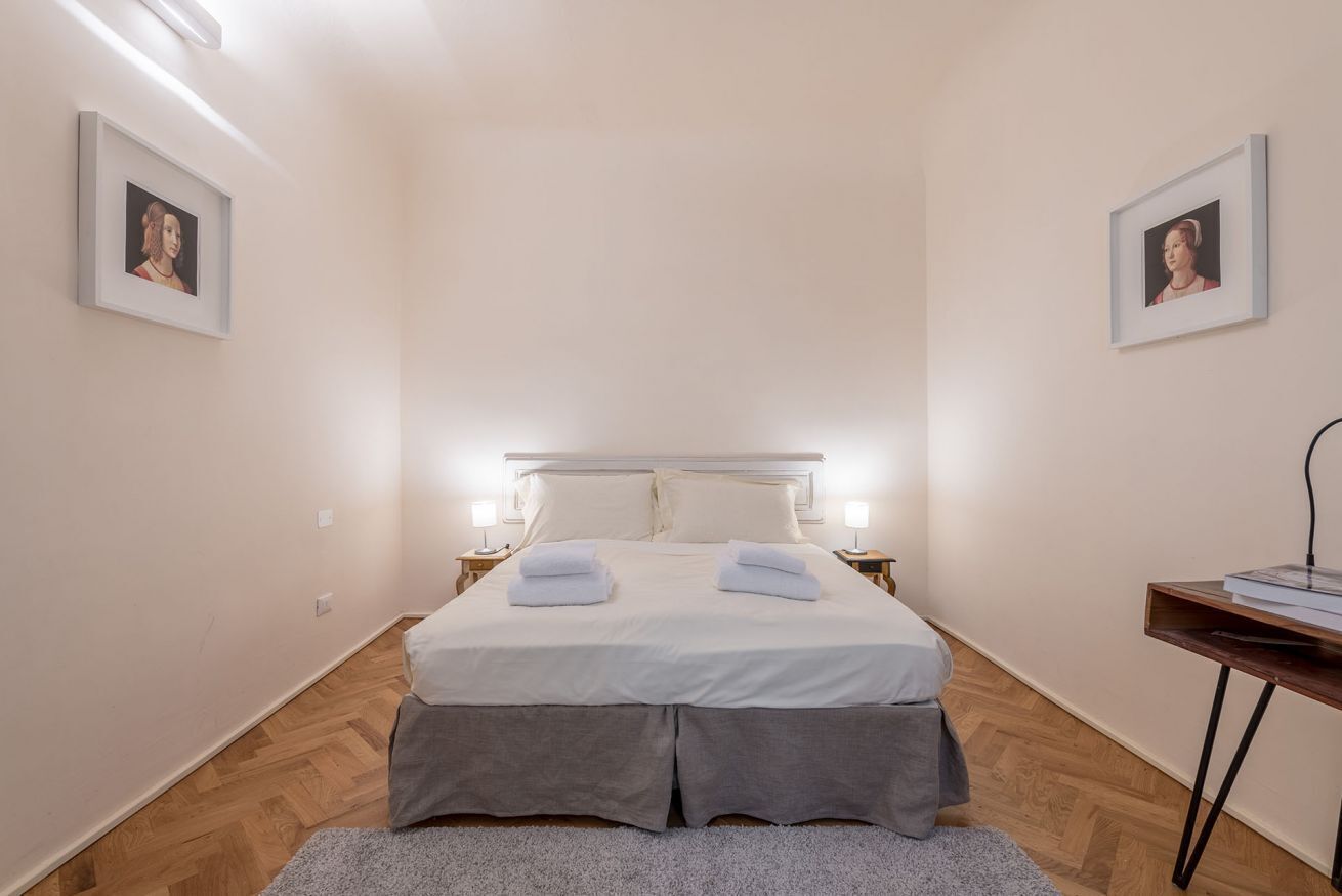 A bedroom with a bed, bedside tables, and framed pictures on the walls.