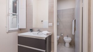 A modern bathroom with a sink, mirror, and bidet.