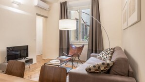 A living room with a sofa, a television, a table, and a chair.