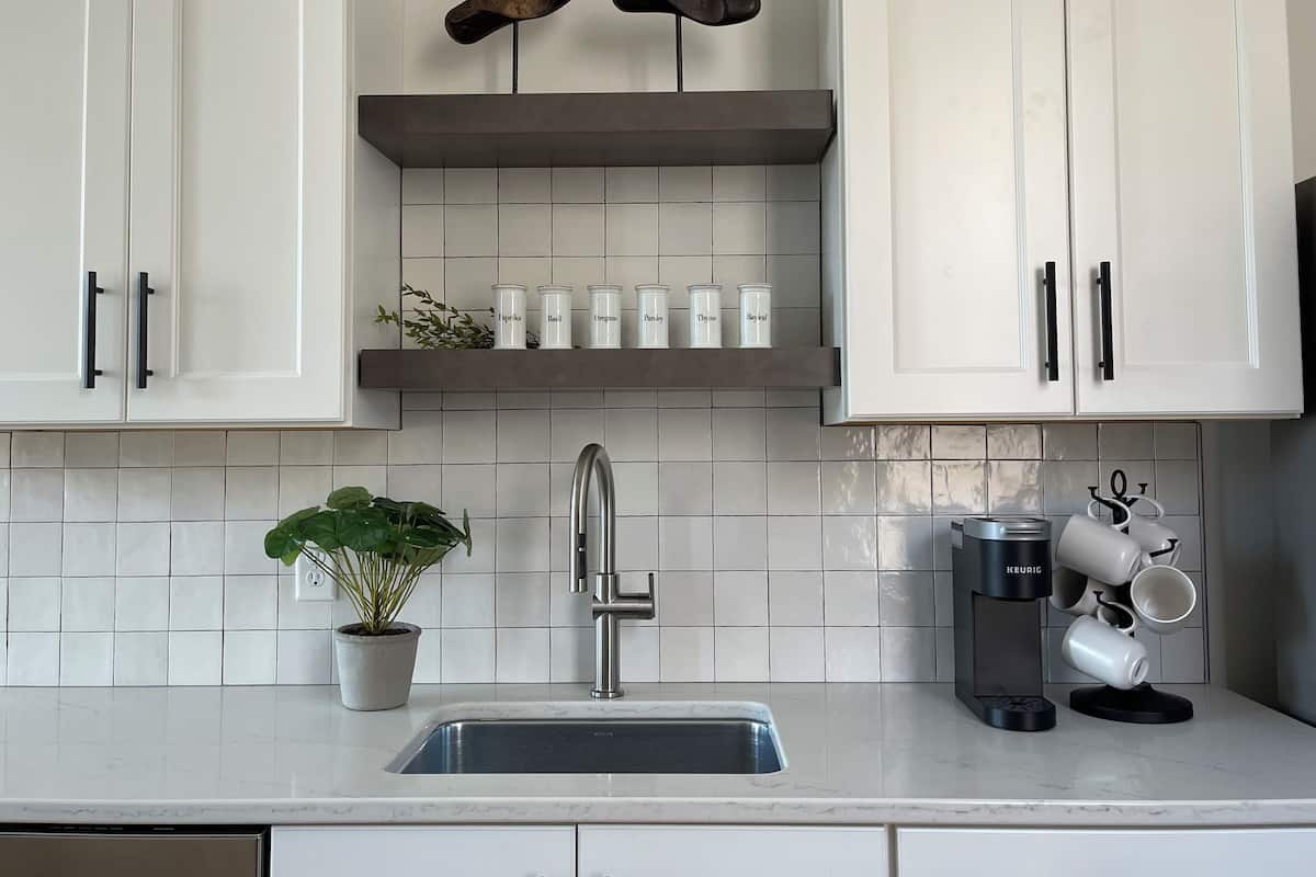 A kitchen with white cabinets, a stainless steel sink, and a coffee machine.